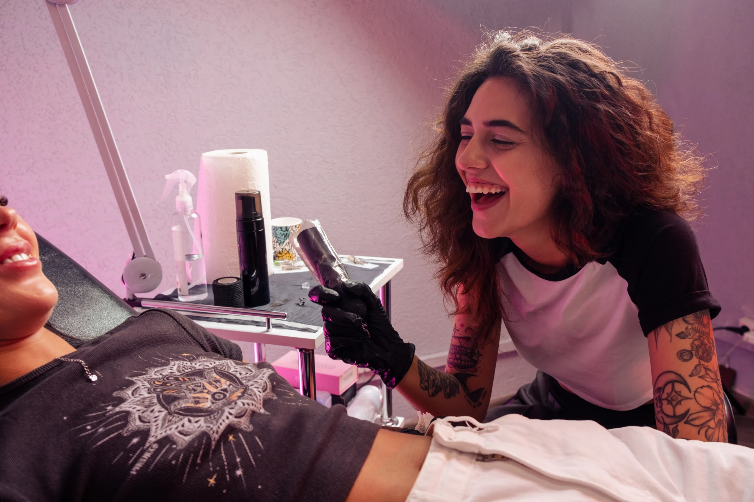 Female tattoo artist at work laughing with a client